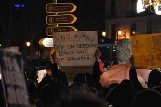 Un manifestante sostiene un cartel escrito por ambos lados.
