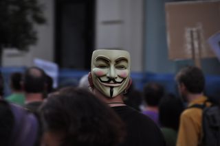 Manifestante con una máscara de Guy Fawkes en la nuca.