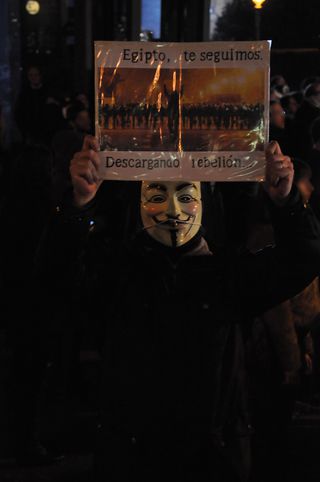 Guy Fawkes sostiene un cartel que llama a la rebelión.