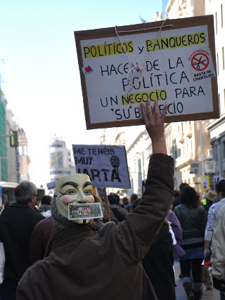 Hombre con una máscara y que sostiene un cartel.